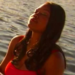 una persona con una camisa roja y una camisa roja con un cuerpo de agua detrás de la