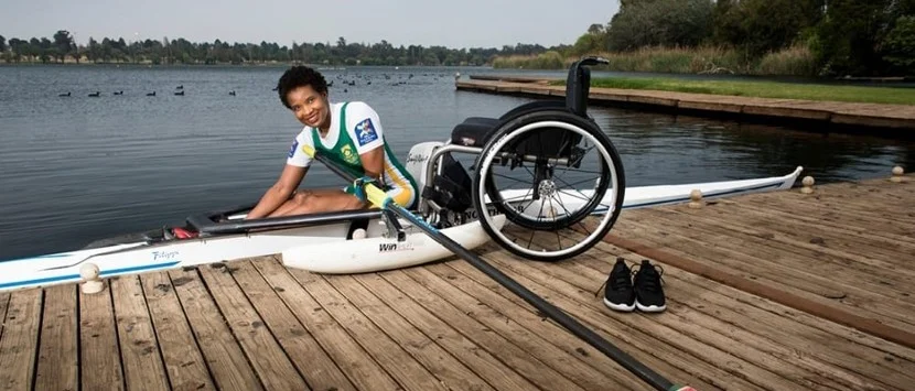 a boy in a wheelchair on a dock by a body of water